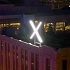 Twitter's new logo, a glowing X, above their San Francisco HQ